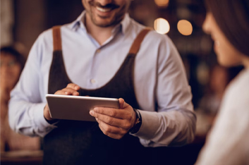 Camarero sonriendo mirando una tablet